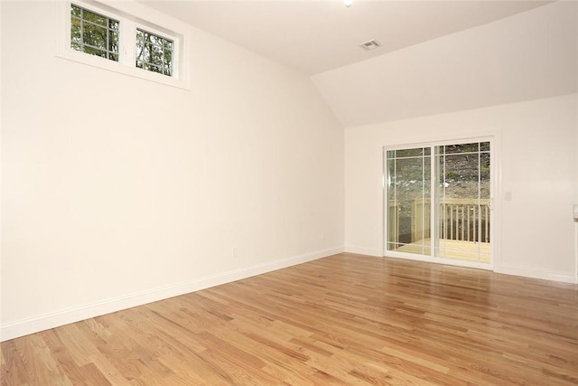 spare room featuring lofted ceiling and light wood-type flooring