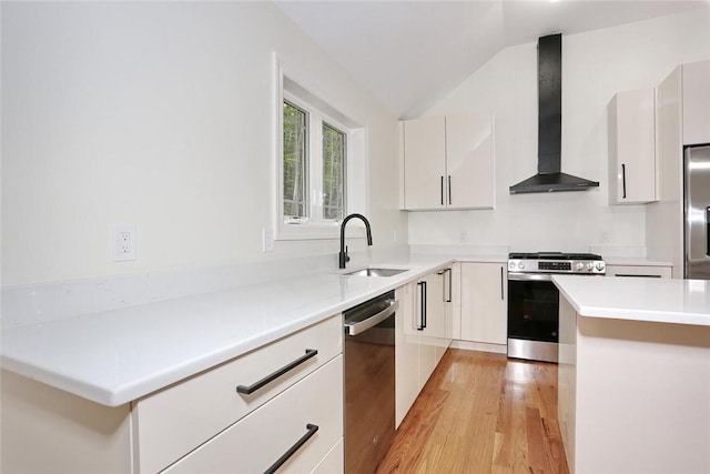 kitchen with white cabinets, light wood-type flooring, stainless steel appliances, and wall chimney exhaust hood