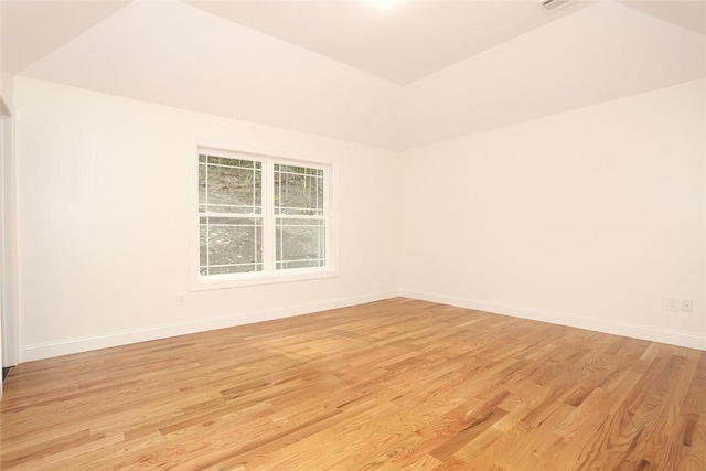 empty room with light hardwood / wood-style flooring and vaulted ceiling