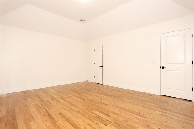 spare room featuring light hardwood / wood-style flooring and lofted ceiling