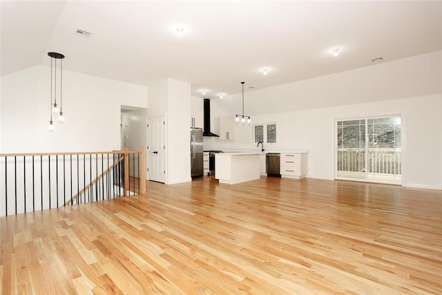 unfurnished living room with light hardwood / wood-style flooring, vaulted ceiling, and sink