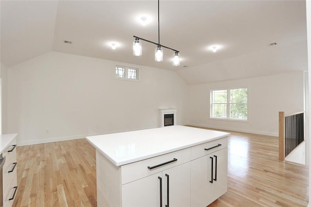 kitchen featuring a kitchen island, white cabinets, lofted ceiling, and light wood-type flooring