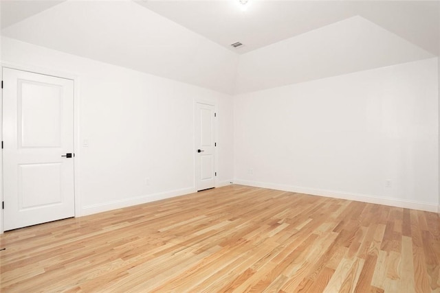 unfurnished room with light hardwood / wood-style floors and vaulted ceiling