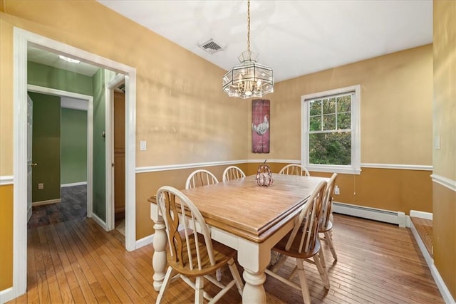 dining room featuring hardwood / wood-style floors, a chandelier, and a baseboard heating unit