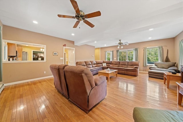 living room with ceiling fan, sink, and light hardwood / wood-style flooring