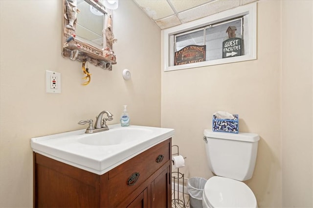 bathroom featuring vanity, toilet, and a drop ceiling