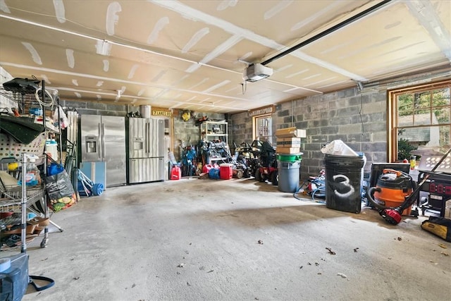 garage with stainless steel fridge with ice dispenser and a garage door opener