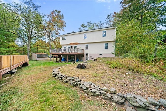 rear view of house with a lawn, a deck, and a storage unit