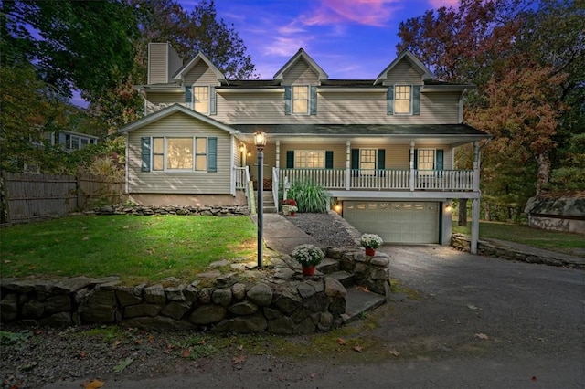 view of front of home with covered porch, a garage, and a lawn