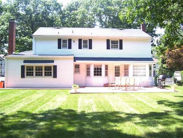 rear view of house with a lawn and a patio