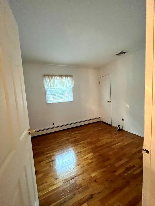 unfurnished room featuring a baseboard radiator and dark hardwood / wood-style floors