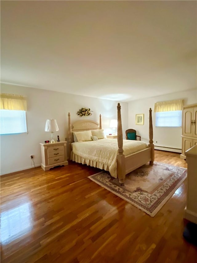 bedroom with hardwood / wood-style flooring and a baseboard heating unit