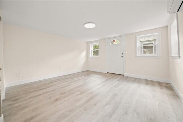 foyer featuring a wall mounted air conditioner and light hardwood / wood-style flooring