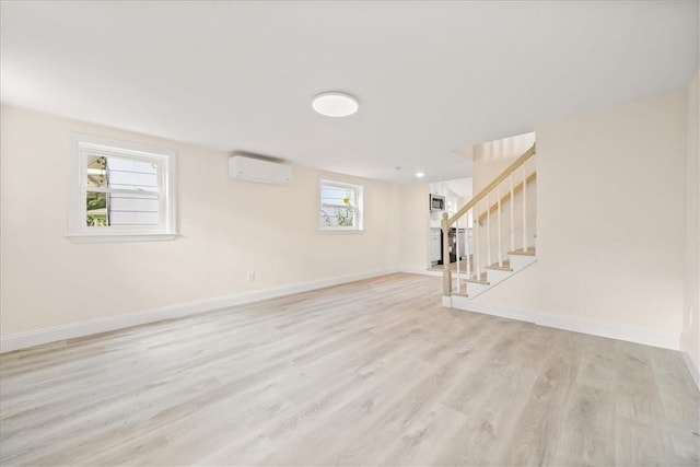 basement featuring a wall mounted air conditioner and light hardwood / wood-style flooring