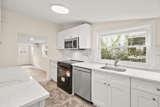 kitchen featuring white cabinetry, sink, light stone counters, and appliances with stainless steel finishes