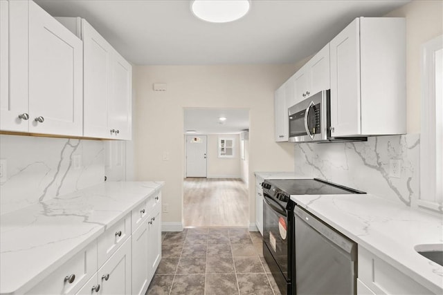 kitchen with tasteful backsplash, tile patterned floors, light stone counters, stainless steel appliances, and white cabinets