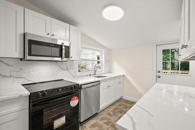 kitchen featuring white cabinetry, sink, light stone counters, backsplash, and appliances with stainless steel finishes