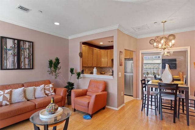 living room with an inviting chandelier, crown molding, and light hardwood / wood-style flooring