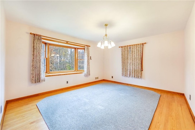 unfurnished room with hardwood / wood-style flooring and an inviting chandelier