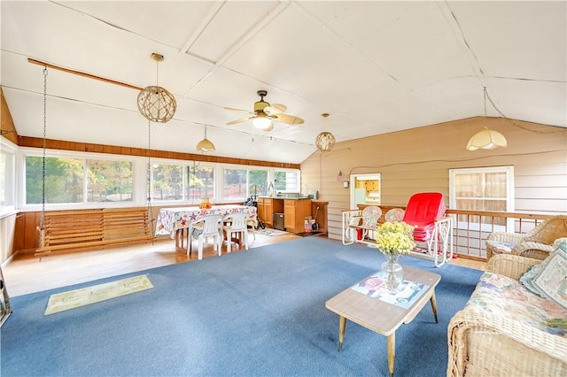 living room featuring ceiling fan, wooden walls, and lofted ceiling