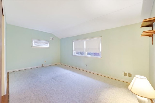 unfurnished room with a healthy amount of sunlight, vaulted ceiling, and carpet