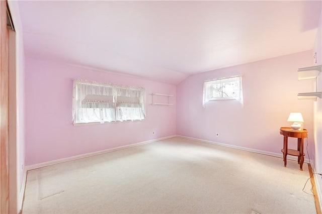 spare room with light carpet and vaulted ceiling