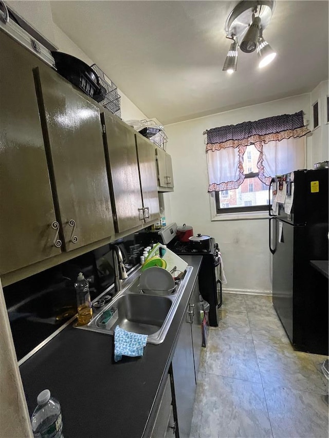 kitchen featuring a sink, gas stove, and freestanding refrigerator