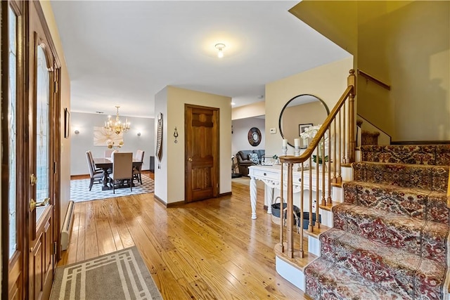 entrance foyer featuring light hardwood / wood-style floors, a baseboard heating unit, and a chandelier