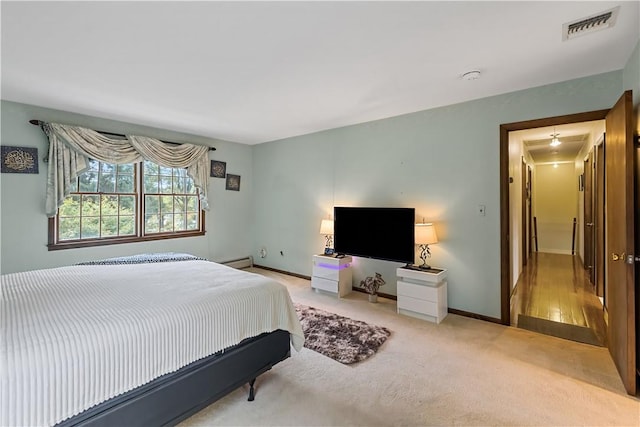 bedroom featuring baseboard heating and light colored carpet