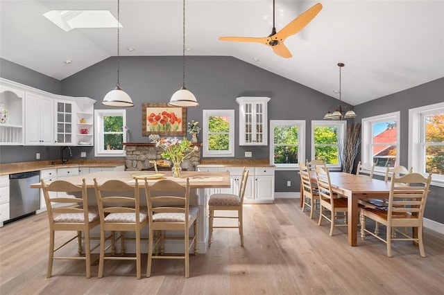 kitchen featuring pendant lighting, light wood-type flooring, white cabinetry, and stainless steel dishwasher