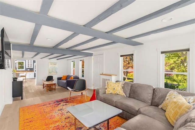 living room with light hardwood / wood-style floors, beam ceiling, and a wealth of natural light