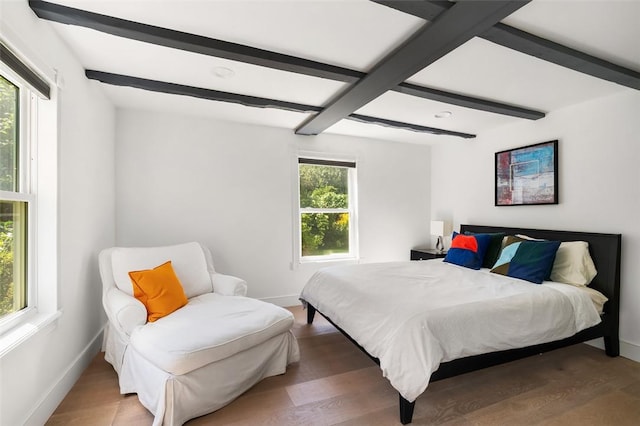 bedroom with beamed ceiling, hardwood / wood-style floors, and multiple windows