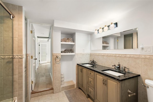 bathroom with vanity, a shower with door, tile walls, tile patterned flooring, and toilet