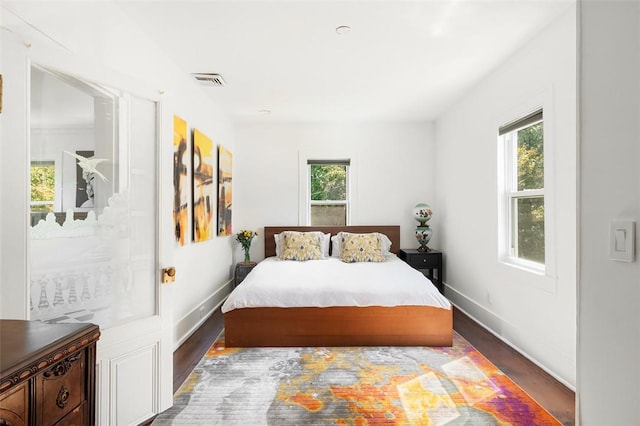 bedroom with dark hardwood / wood-style floors and multiple windows