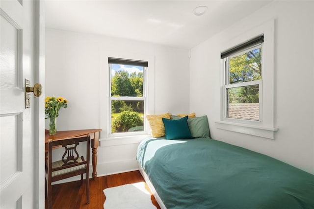 bedroom with multiple windows and dark wood-type flooring