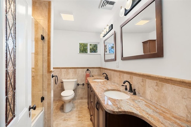 full bathroom featuring shower / bathing tub combination, vanity, toilet, and tile walls