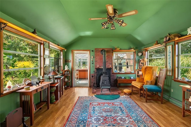 sunroom with a wood stove, plenty of natural light, and lofted ceiling