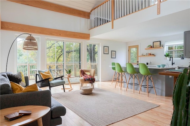 living room featuring light hardwood / wood-style flooring, beamed ceiling, and a healthy amount of sunlight