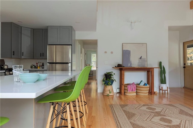 kitchen featuring stainless steel refrigerator, plenty of natural light, gray cabinetry, and light wood-type flooring