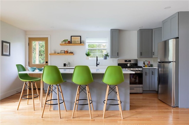 kitchen with a healthy amount of sunlight, light wood-type flooring, stainless steel appliances, and a breakfast bar area