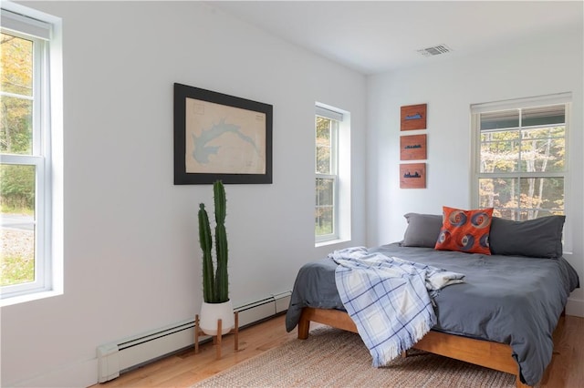 bedroom featuring hardwood / wood-style flooring and baseboard heating