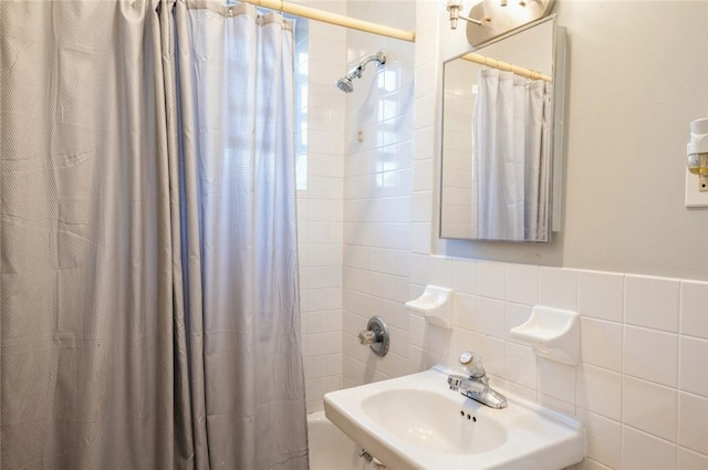 bathroom featuring sink, shower / bath combination with curtain, and tile walls