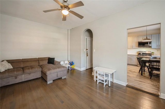 living room with ceiling fan and dark wood-type flooring