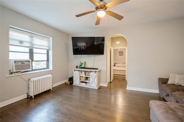 living room with ceiling fan, cooling unit, dark wood-type flooring, and radiator