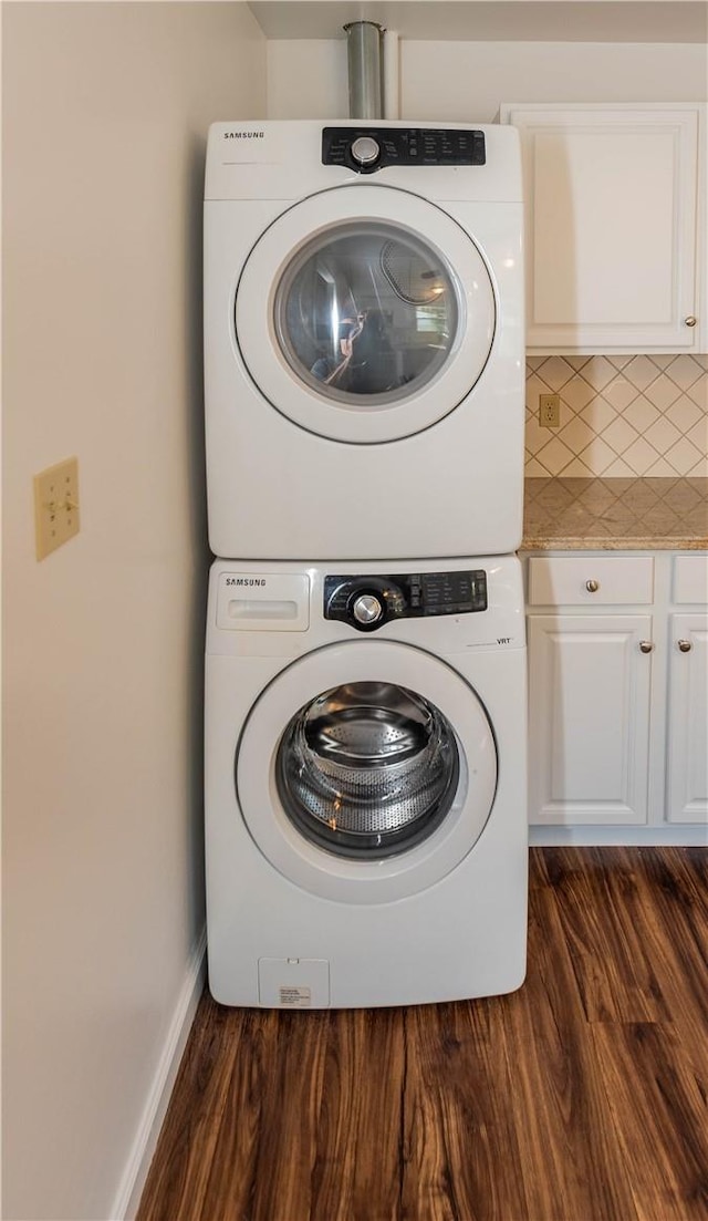 laundry area featuring cabinets, dark hardwood / wood-style flooring, and stacked washer and clothes dryer