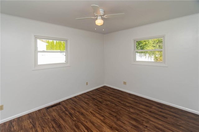 spare room featuring ceiling fan, a healthy amount of sunlight, crown molding, and dark wood-type flooring