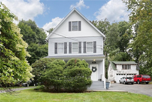 view of front of home featuring a garage, an outbuilding, and a front yard