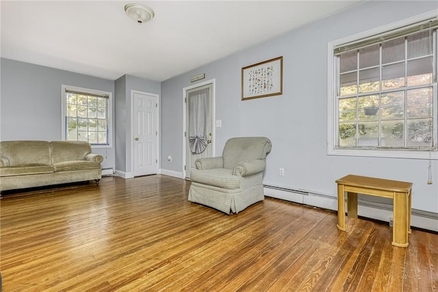 living area with hardwood / wood-style floors and a baseboard heating unit