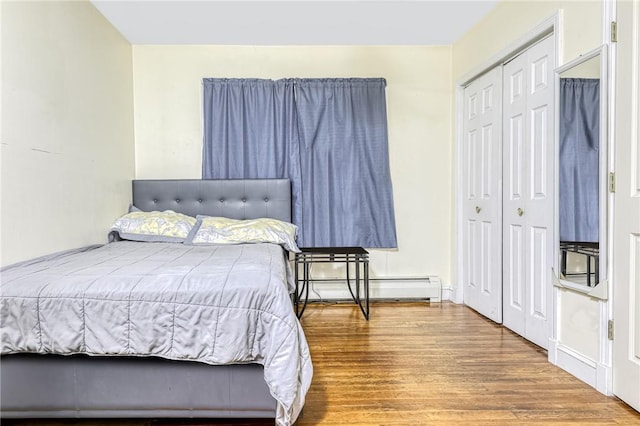 bedroom with hardwood / wood-style floors, a baseboard radiator, and a closet