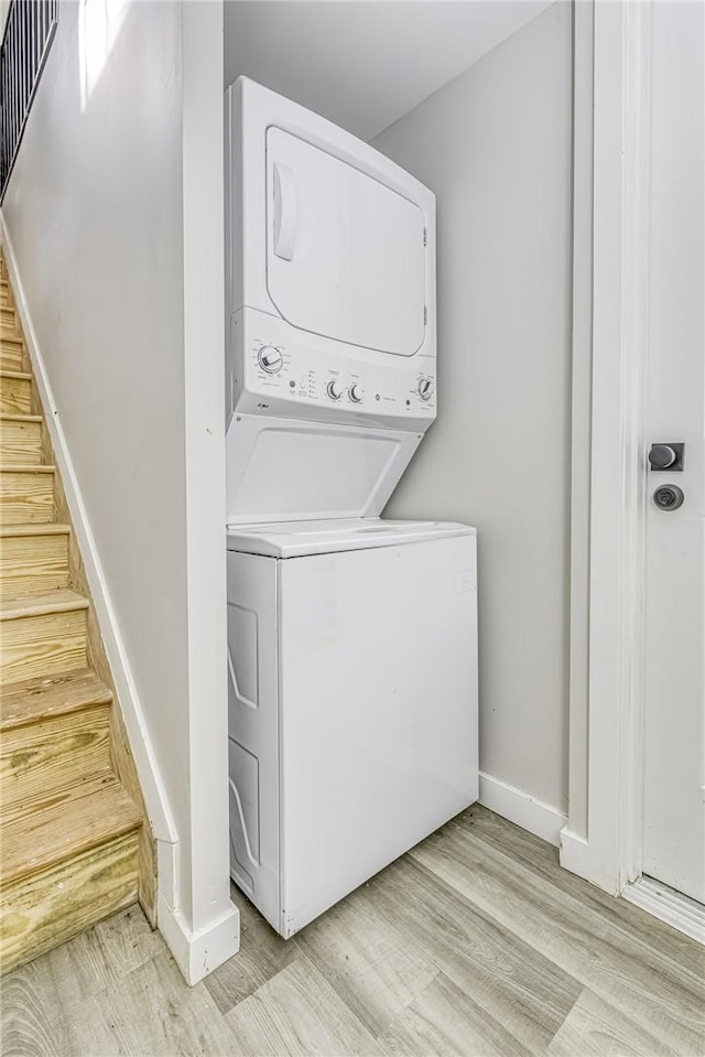 clothes washing area featuring light hardwood / wood-style floors and stacked washer / dryer